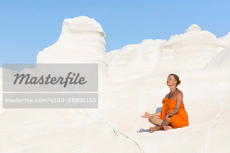 Woman meditating on white rocks