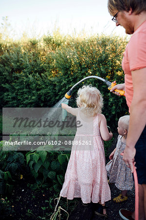 Father with daughters watering vegetables