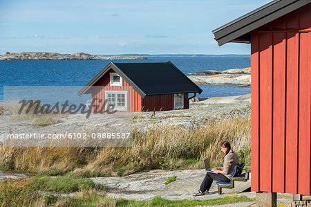 Woman using laptop at coast