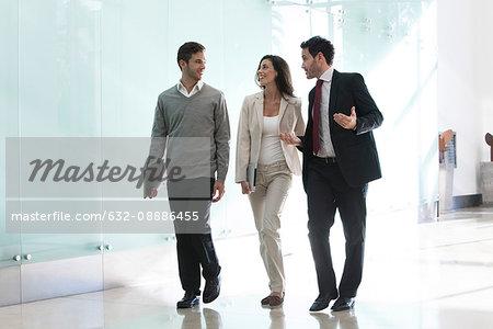 Business associates talking while walking together in office