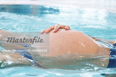 Pregnant woman floating in swimming pool
