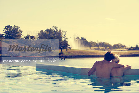 Couple relaxing in infinity pool overlooking lake