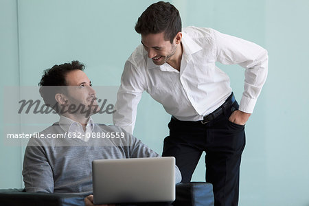 Business professionals looking at laptop computer together