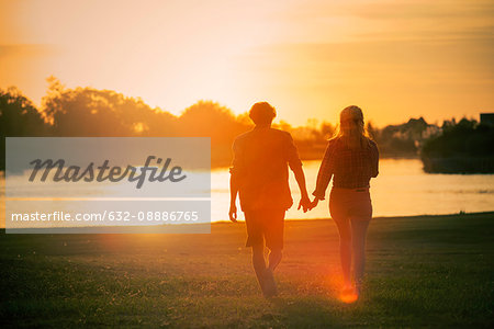 Couple walking hand in hand at water's edge