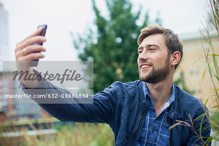 Young man using smartphone to take a selfie outdoors