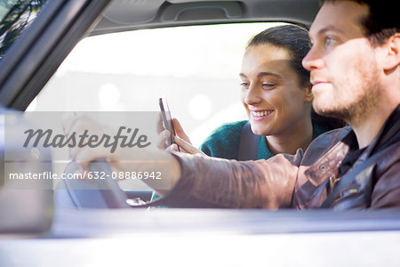 Couple listen to music streaming on smartphone during road trip