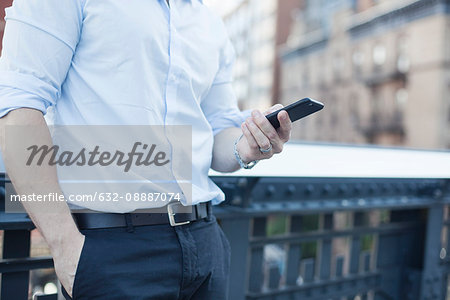 Businessman holding smartphone, mid section