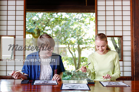 Caucasian couple practicing calligraphy at traditional Japanese house