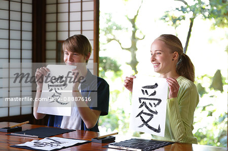 Caucasian couple practicing calligraphy at traditional Japanese house