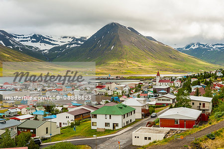 Mighty fjords with mountains covered by snow rise above the town of Olafsfjordur, Northern Iceland