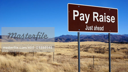 Pay Raise road sign with blue sky and wilderness