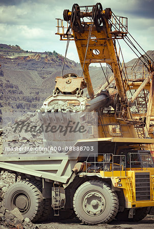 Heavy mining truck and excavator developing the iron ore on the opencast mining site