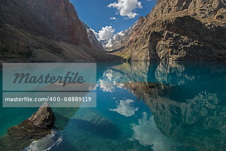 Blue lake surrounded with rocks. Blue sky and clouds reflects in water. Big Alo is the most beauty lake of  Fann Mountains