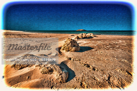 View of a small island from the Israeli shore of the Mediterranean Sea. Sand blowing over beach dune in wind in Israel. Vintage Style Toned Picture