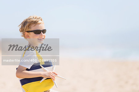 cheerful smiling boy in sunglasses holding beach bag and starfish at the beach with copyspace on the right side, vacation concept