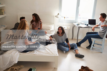 Five teenage friends hanging out together in bedroom