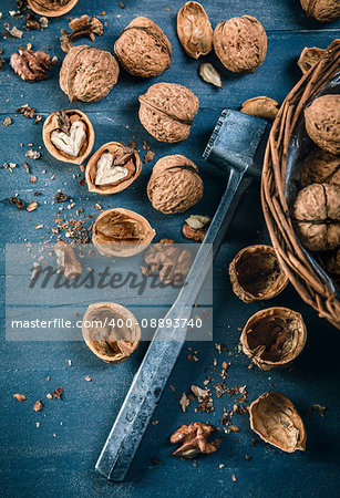 Walnut in wicker basket on blue old wooden board rustic style with nutshell top view.