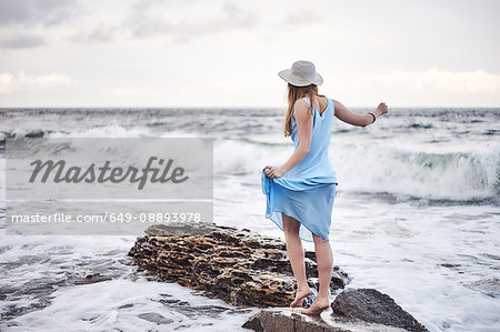 Woman enjoying walk on rocks in sea