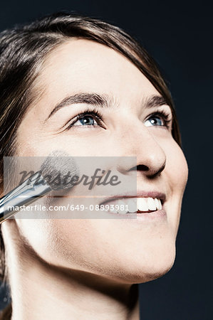 Face powder being applied to young woman's cheek