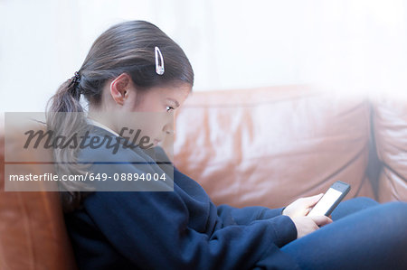 Girl playing with smartphone on sofa