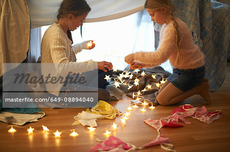 Two sisters in bedroom den preparing star shape lights