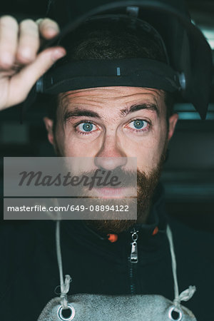Portrait of male metalworker holding up welding mask