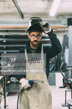 Portrait of metalworker holding welding torch in forge workshop