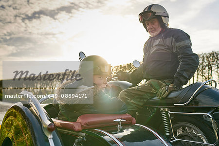 Senior man and grandson looking back from motorcycle and sidecar