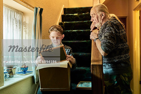 Senior man explaining to grandson sitting on stairs with photograph frame