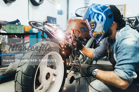 Mature man, working on motorcycle in garage