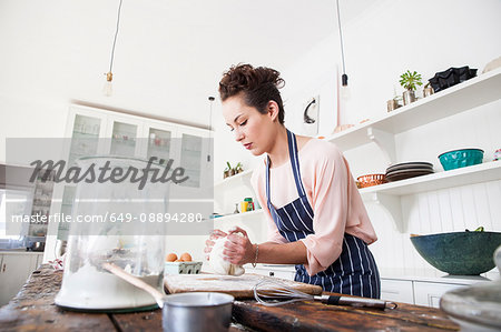 Young woman kneading dough at kitchen counter