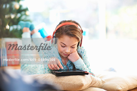 Girl lying on living room floor looking at digital tablet at christmas