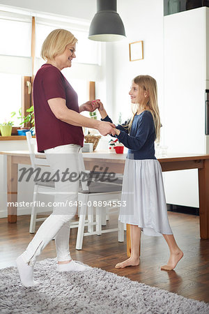 Grandmother and granddaughter dancing at home