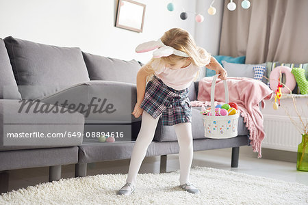 Girl finding easter eggs under sofa cushion