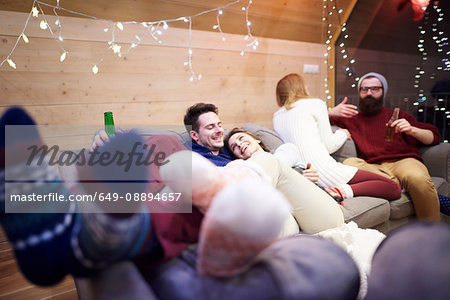 Friends enjoying being together on sofa in chalet