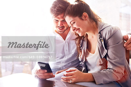 Businessman and woman looking at smartphone in office