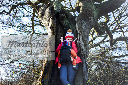 Woman in hollow tree, carrying young baby in sling