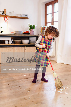Cute girl sweeping kitchen floor