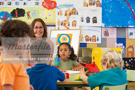 Preschool boys and girls building with toy blocks in classroom