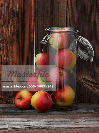 Fresh apples inside and next to a glass storage jar