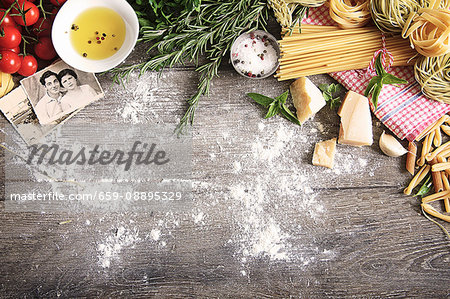 An arrangement of typical Italian food items and family photos on a wooden table