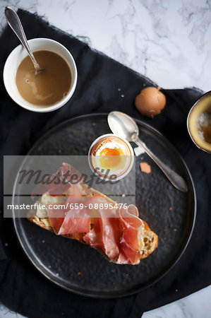 Breakfast with a soft-boiled egg and bread with ham