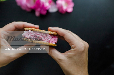 Hands holding cherry ice cream sandwich with waffles