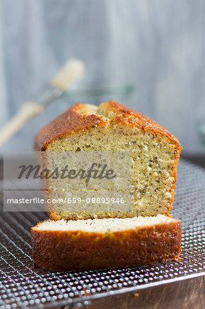 A lemon and poppyseed loaf cake on a wire cooling rack (with one slice cut off)