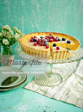 Lemon tart topped with berries with a slice taken out