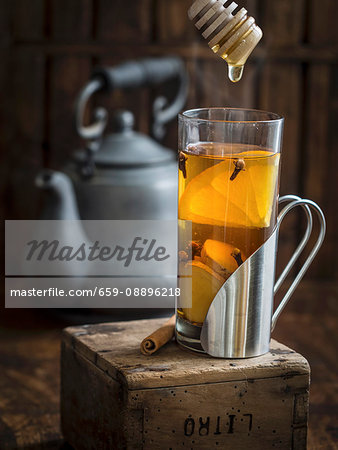 Cup of hot winter spiced tea with honey on a rustic background