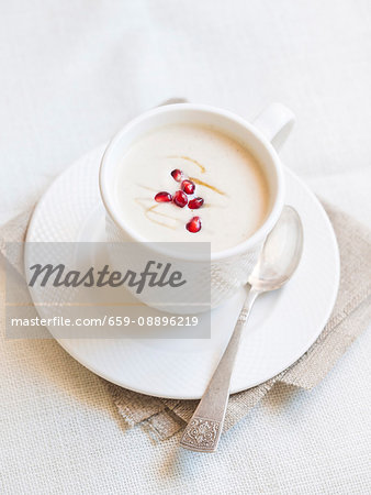 Cup of cauliflower cream soup served with pomegranate