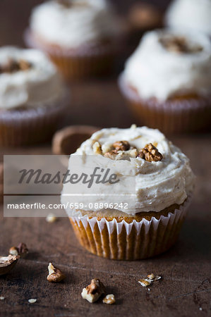 Pumpkin cupcake with cream cheese frosting and walnuts.