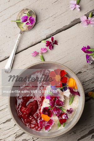 A breakfast of porridge with strawberry compote and fresh edible flowers (seen from above)