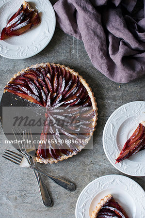 Plum tart dusted in icing sugar with slices cut out